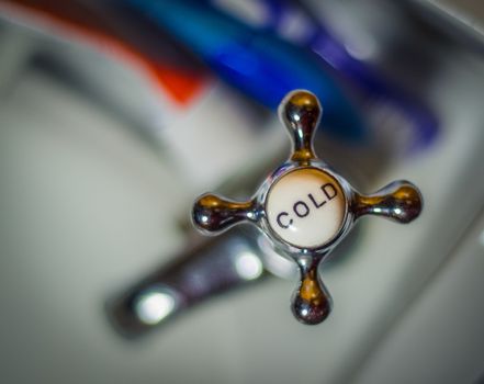 Detail Of A Rustic VIntage Cold Faucet And Toothbrushes On A Wash Basin