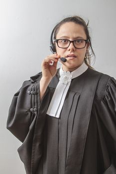 thirty something brunette woman wearing a canadian lawyer toga with a telephone headset on her head