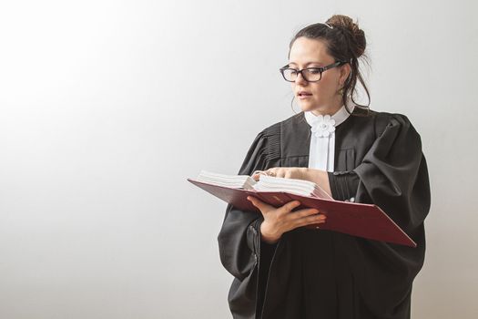 thirty something brunette woman wearing a canadian lawyer toga, reciting from a red criminal law book