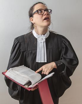 thirty something brunette woman wearing a canadian lawyer toga with a red criminal law book in hand