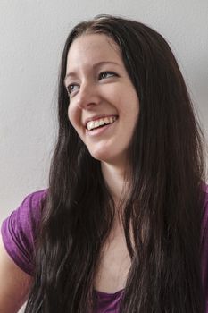 young woman with long black hair against a white wall