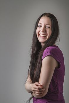 young woman with long black hair and a purple shirt laughing and holding her stomach