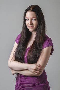 young woman with long black hair and a purple shirt with her arms cross