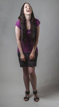 young woman with long black hair and a purple shirt laughing out loud