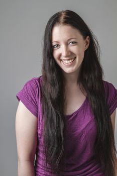 young woman with long black hair and a purple shirt with great big smile