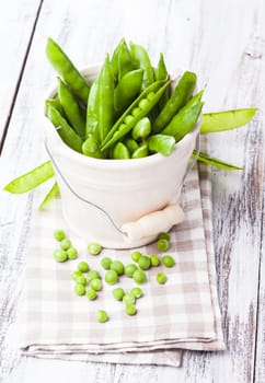 Green pea scattered on the napkin and unpeeled pea