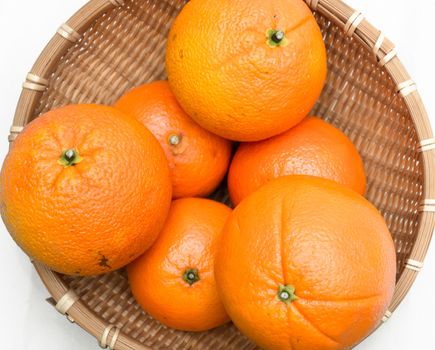 Some oranges lying inside a net basket isolated on white background