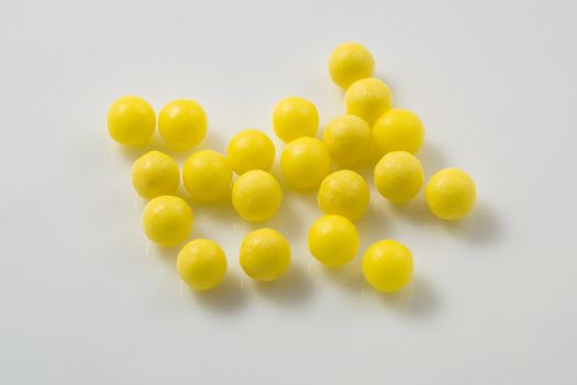 Yellow pills scattered on a white background.