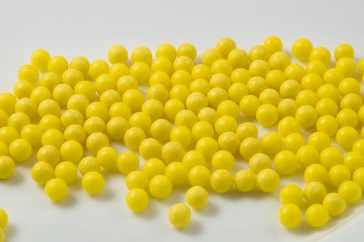 Yellow pills scattered on a white background.