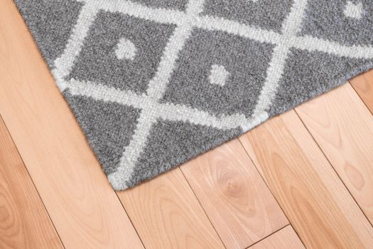 Contemporary gray wool rug on wooden floor.