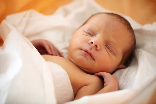 Cute four-day old baby boy asleep in his bed