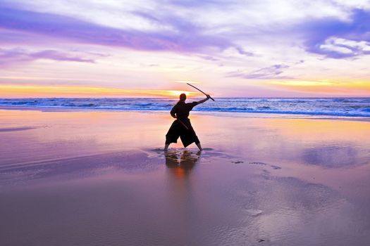 Young samurai women with Japanese sword(Katana) at sunset on the beach