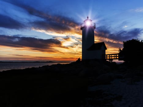 Annisquam lighthouse located in massachusetts, back lit by sunset