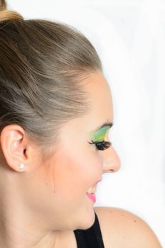 Aside photo, portrait of young female model with gentle smile on her face. Girl with colorful makeup.