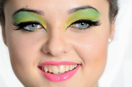 Smiling face photo of young female model with colorful make-up. Young girl with cheering smile.
