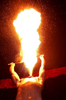 Circus fire-eater blowing a large flame from his mouth