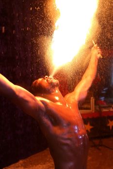 Circus fire-eater blowing a large flame from his mouth