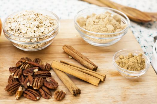 Ingredients for apple crumble, pecans, cinnamon sticks, sugar, spices and oats.