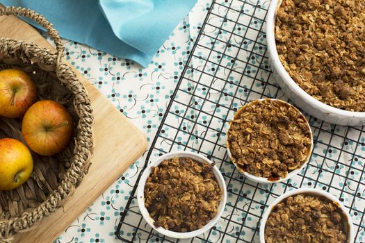 Single serving and larger dish of apple crumble cooling on rack, viewed from above