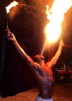 Circus fire-eater blowing a large flame from his mouth