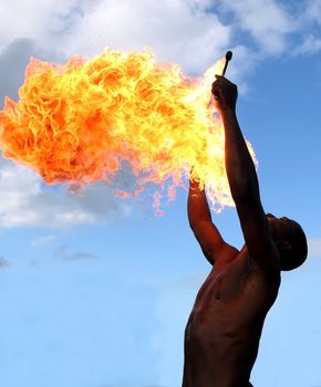 Circus fire-eater blowing a large flame from his mouth