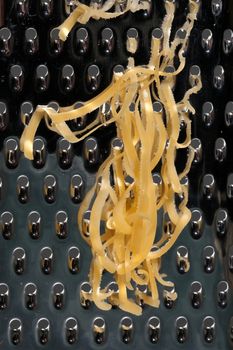 Close up of cheese grated on a stainless steel kitchen grater