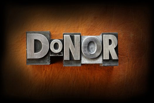 The word donor made from vintage lead letterpress type on a leather background.