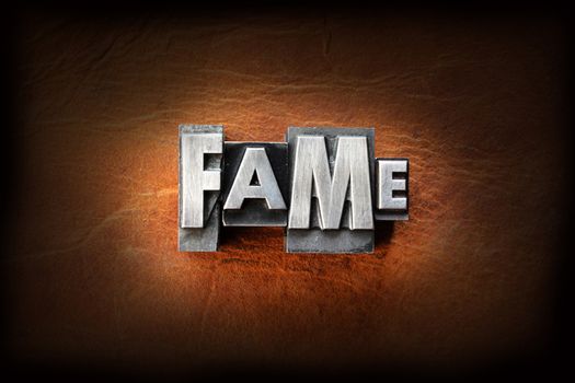 The word fame made from vintage lead letterpress type on a leather background.