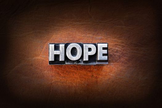 The word hope made from vintage lead letterpress type on a leather background.