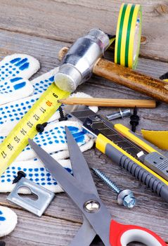 Heap of Work Tools with Measuring Tape, Pencil, Scissors, Hammer, Protective Gloves and Screw on Rustic Wooden background