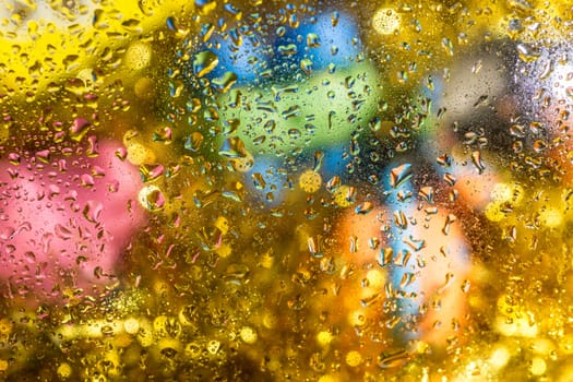 A bright colorful background image of water droplets on a glass surface