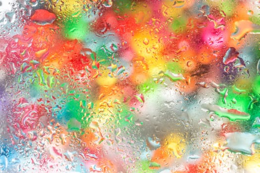 A bright colorful background image of water droplets on a glass surface