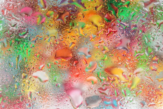 A bright colorful background image of water droplets on a glass surface