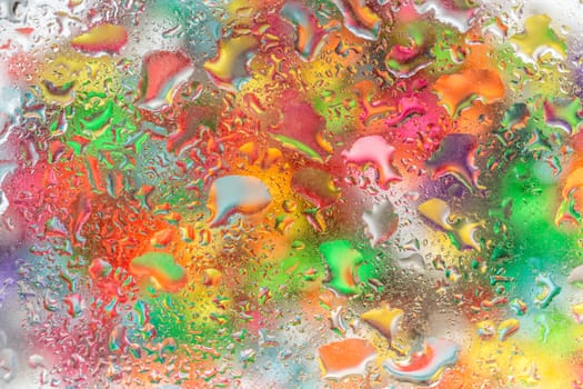 A bright colorful background image of water droplets on a glass surface