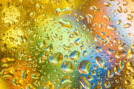 A bright colorful background image of water droplets on a glass surface