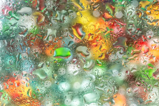 A bright colorful background image of water droplets on a glass surface