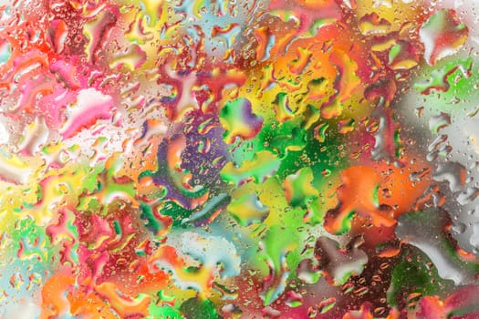 A bright colorful background image of water droplets on a glass surface