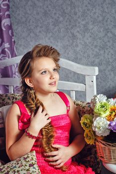 Beautiful little girl in a pink dress with a bouquet of flowers posing in the interior