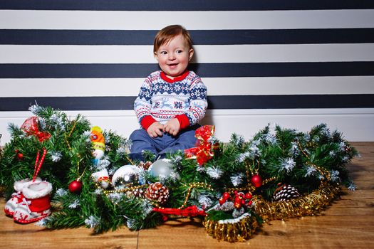 Little boy sitting on the floor surrounded by Christmas decorations