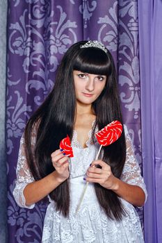 Attractive young brunette girl holding a lollipop with heart-shaped