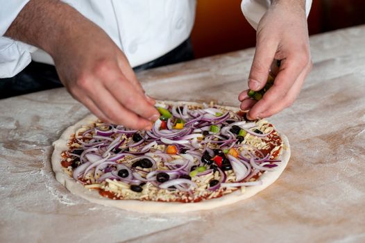 Chef spreading onion on pizza base