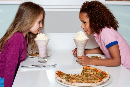 Little girls drinking strawberry shake in a restaurant