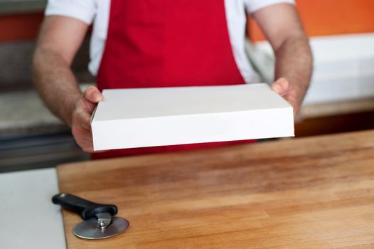 Chef handing over pizza, cropped image