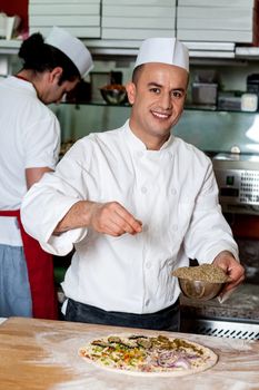Experienced chef preparing pizza in kitchen