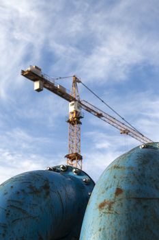 Blue pipelines with bolts at construction site with crane in background