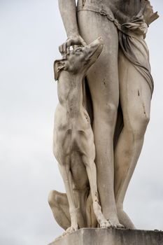 Close up of a statue with dog and a pair of legs