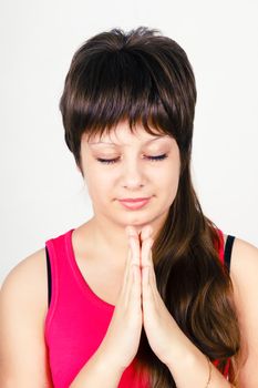 Young attractive girl praying with clasped hands together