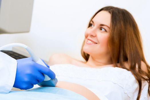 close-up of hands and abdominal ultrasound scanner for pregnant women