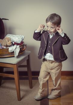 Vintage portrait of cute little boy playing with antique glasses found in a old case. Retro style concept.