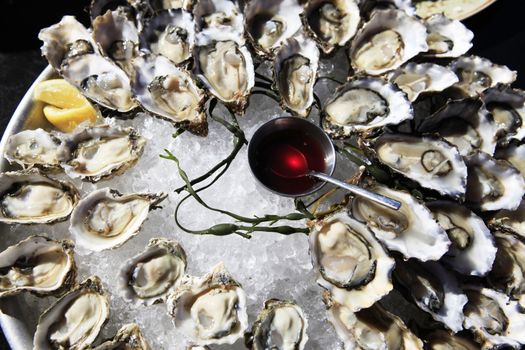 Opened oysters on ice with red souse